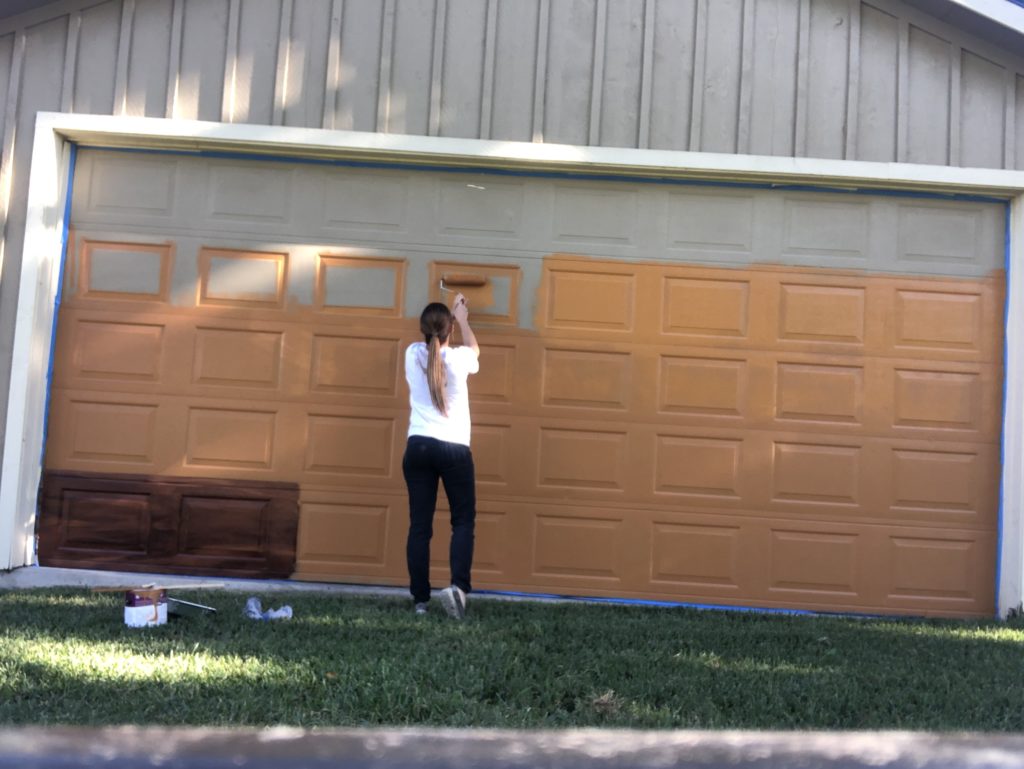 Shelby rolling on the orange base coat on the garage door for the faux wood painting project